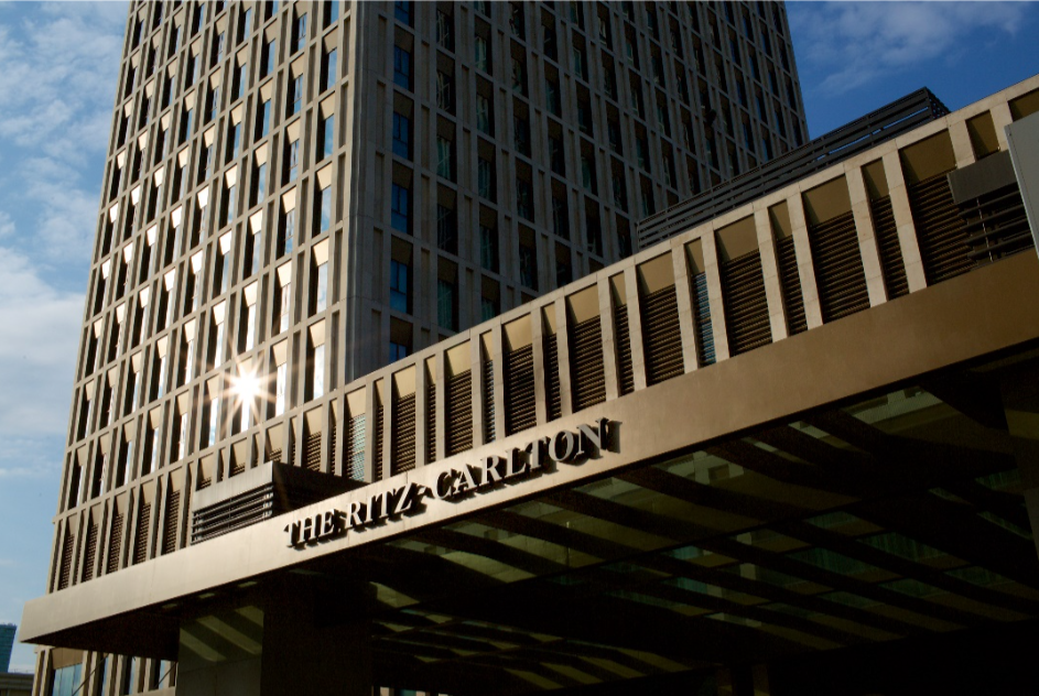 Exterior view of The Ritz-Carlton building under a sunny sky, featuring a tall modern structure with a prominent sign.