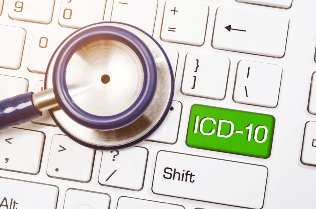 A stethoscope rests on a computer keyboard with a green key labeled "ICD-10" next to the Shift key, symbolizing the integration of healthcare outsourcing services in modern medical practices.