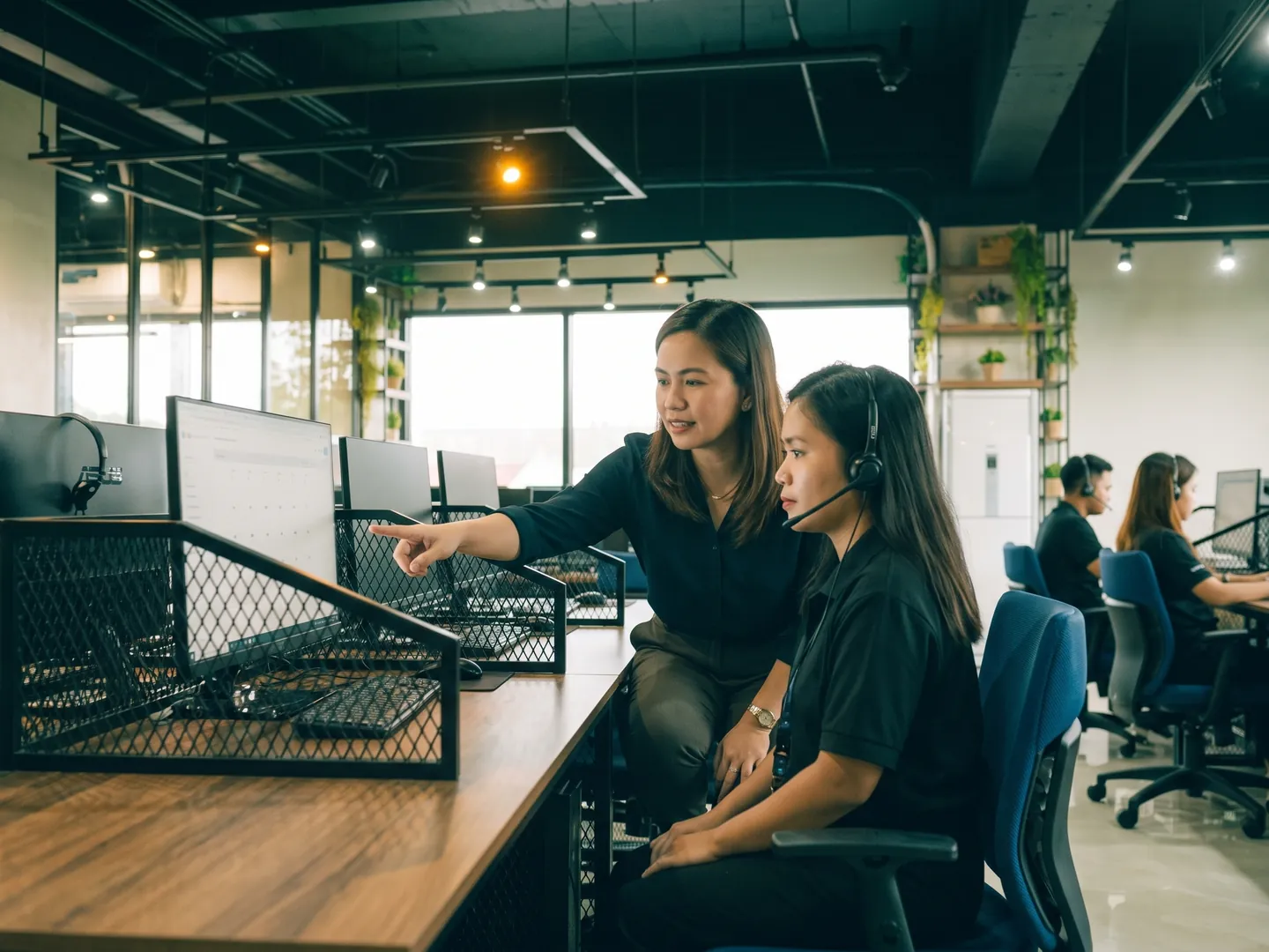 A team leader coaching a healthcare support agent at her desk in a Naga City office