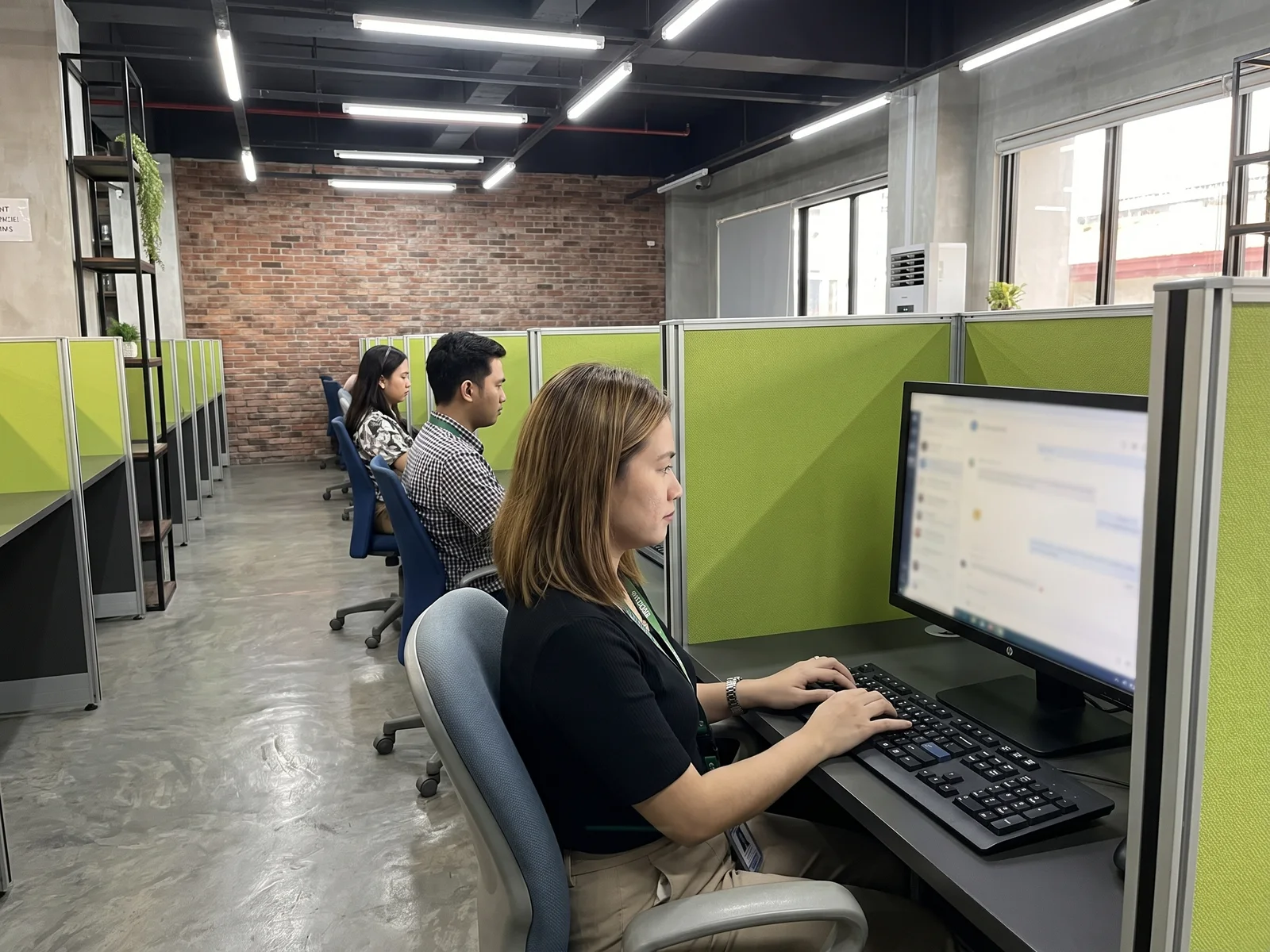 Chat agents typing at their cubicles in a Naga City office