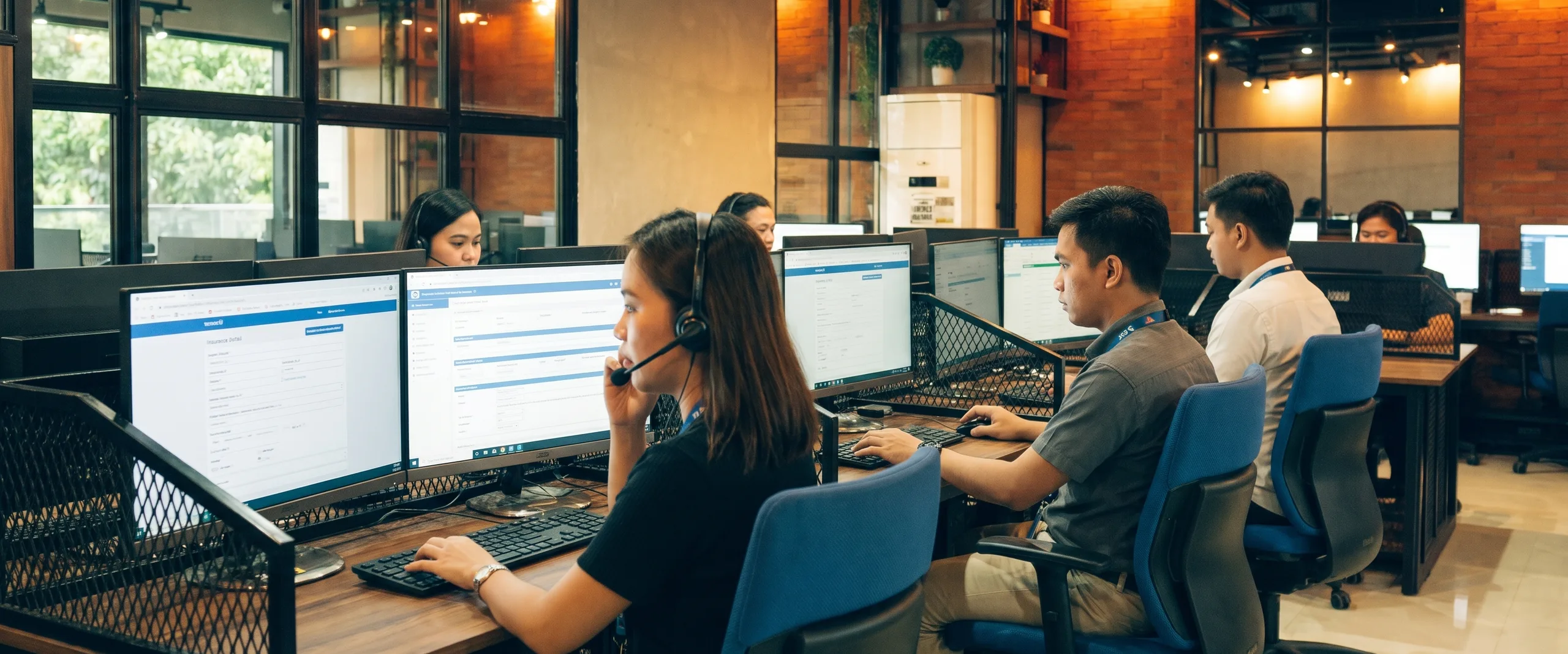 Prior authorization specialists working insurance portals and patient records on an office floor in Naga City